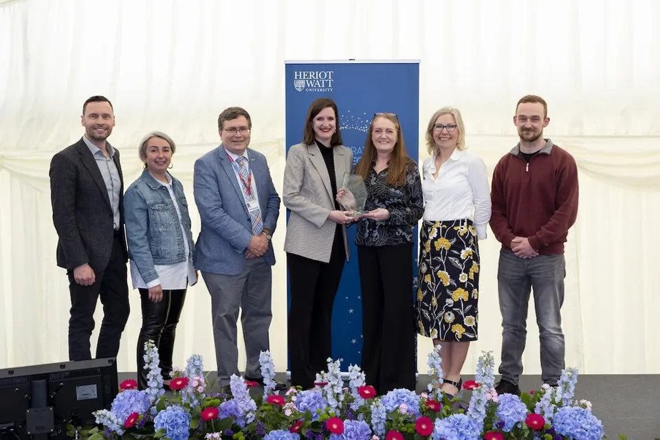 Seven individuals smiling as they receive an award. 