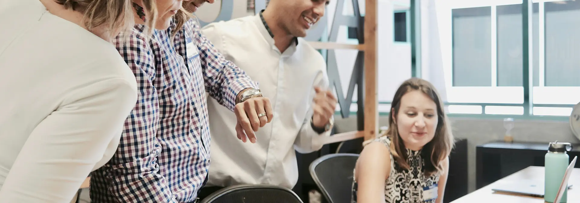 Several staff members looking at a laptop screen of a colleague