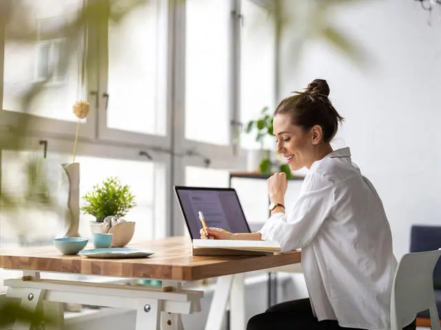 An individual works in a bright room on a laptop