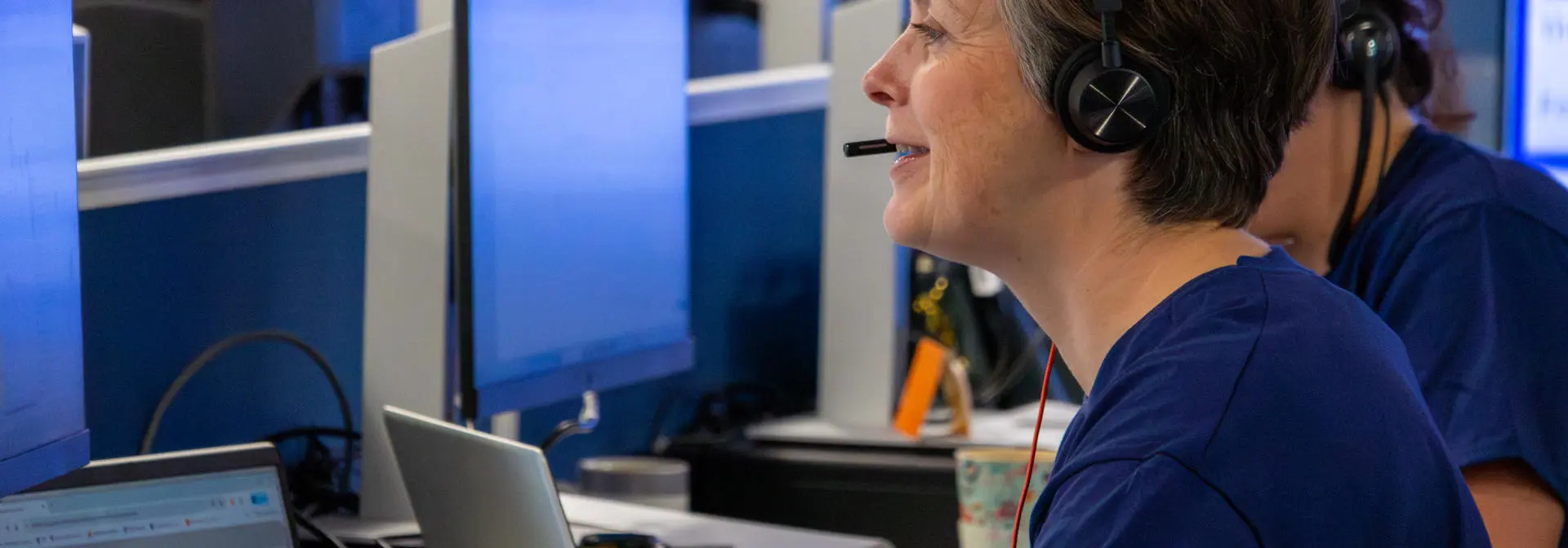 Staff working at a computer in an office with a headset.