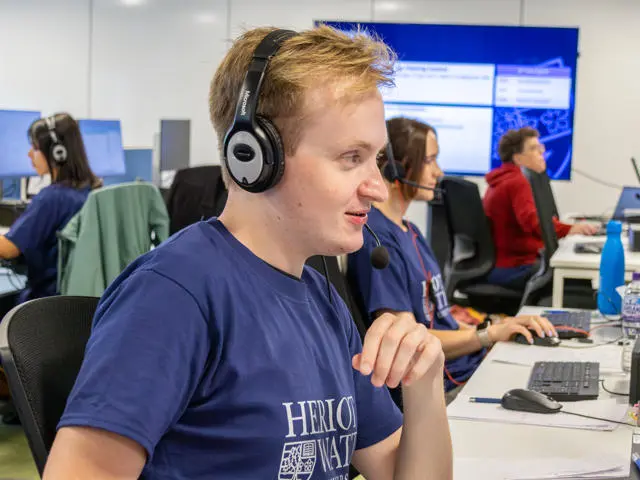 Staff working at a computer in an office with a headset.