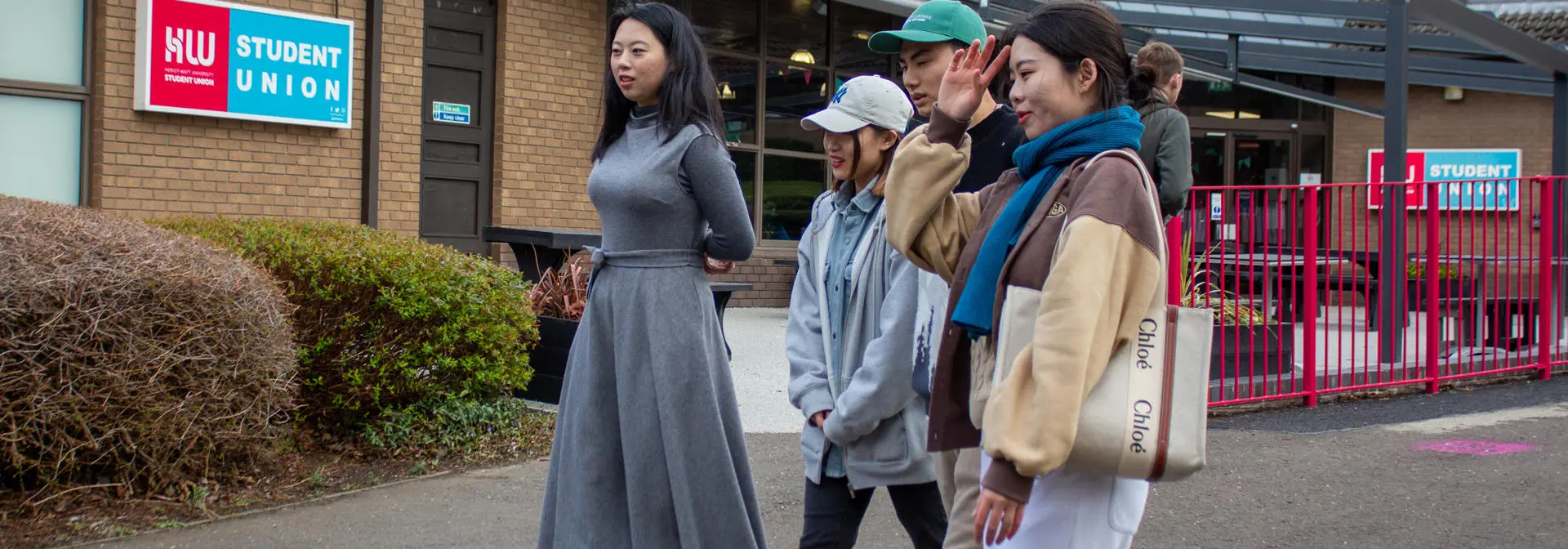 Four individuals waking beside the Student Union building