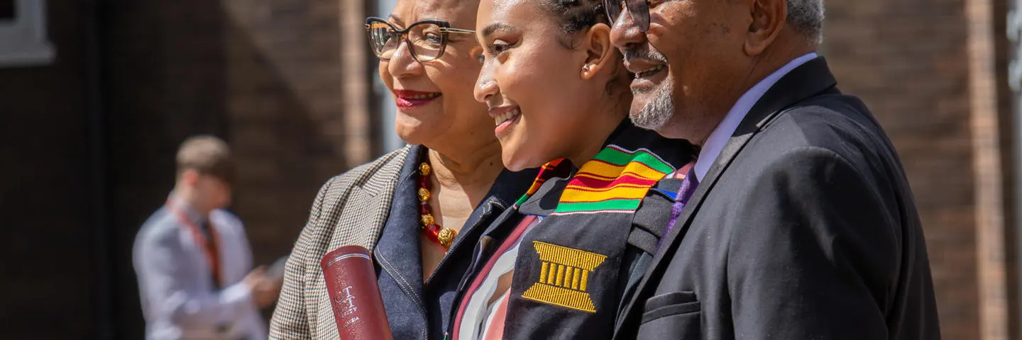A student poses with her parents at graduation in Edinburgh.