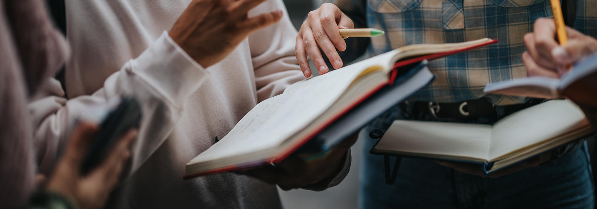 Three students in a group discussion holding books.