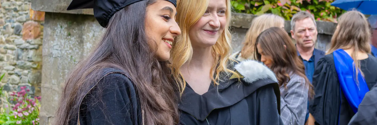 Students in graduation robes post for photographs.