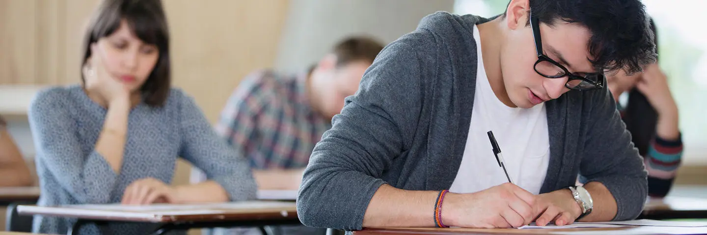 Students in an exam hall writing answers.