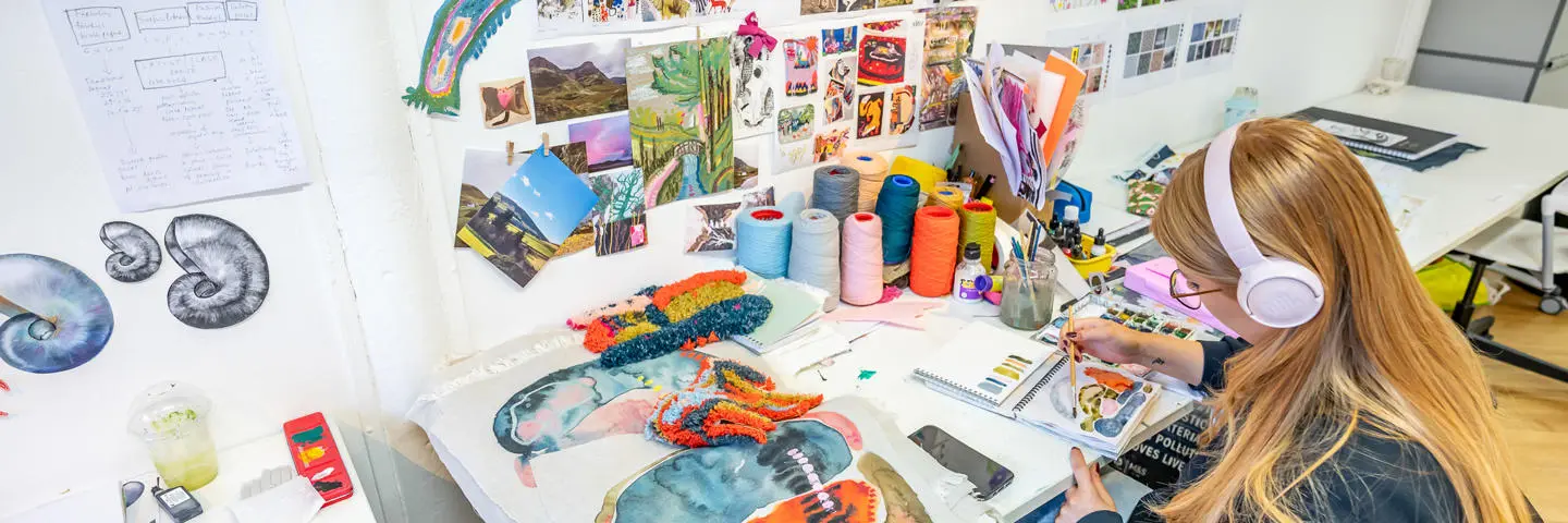 An individual paints with multiple different vibrant colours while listening to music.