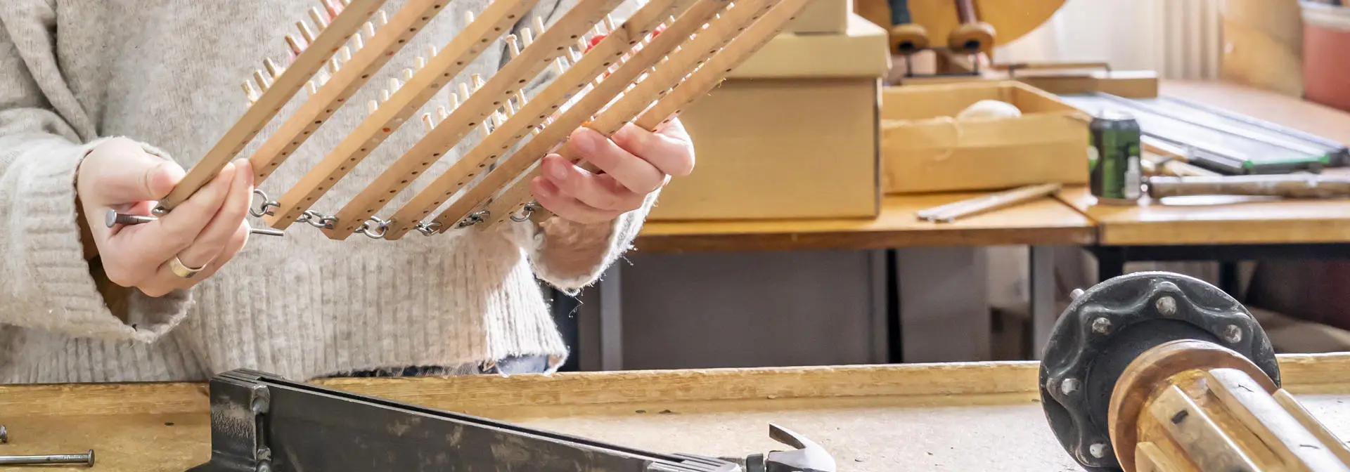 A person holds a weaving tool at a desk.