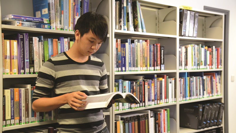 Student in library reading book