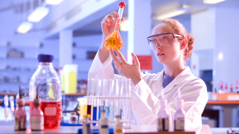 Female student holding equipment in lab