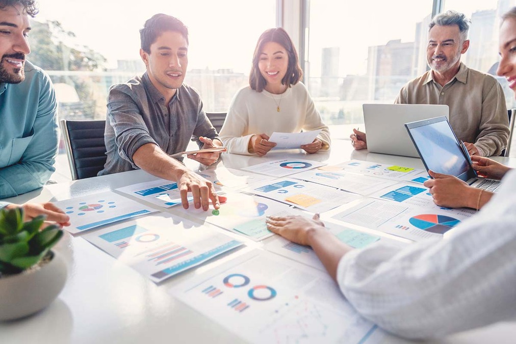 A stock image of people in a meeting looking at charts and graphs