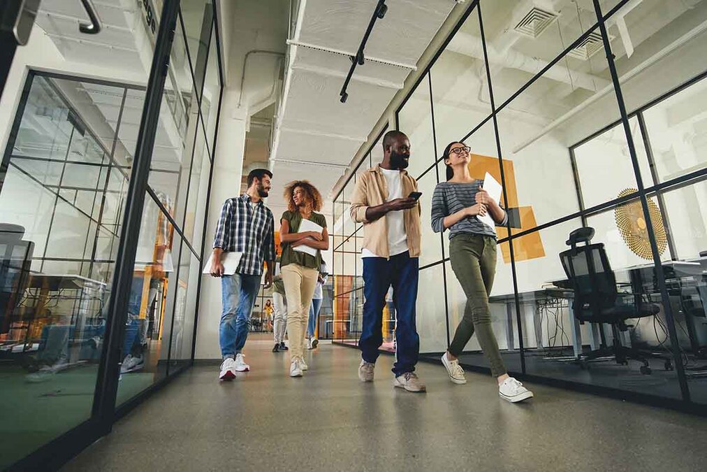 A stock image of four people walking, holding laptops and notebooks and chatting