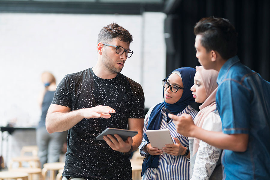 Young man holding a tablet computer gives guidance to a group