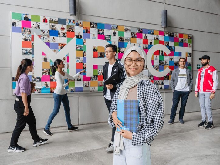 students standing in front of a collage with the word Impact written on it