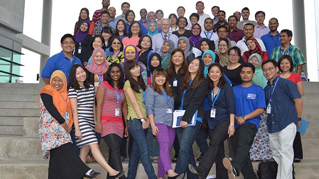 The first staff at the Malaysia Campus form a group on the steps outside the entrance