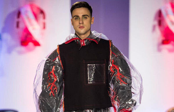 male model walking catwalk, wearing a long oversize clear coat with red seams and a black undershirt