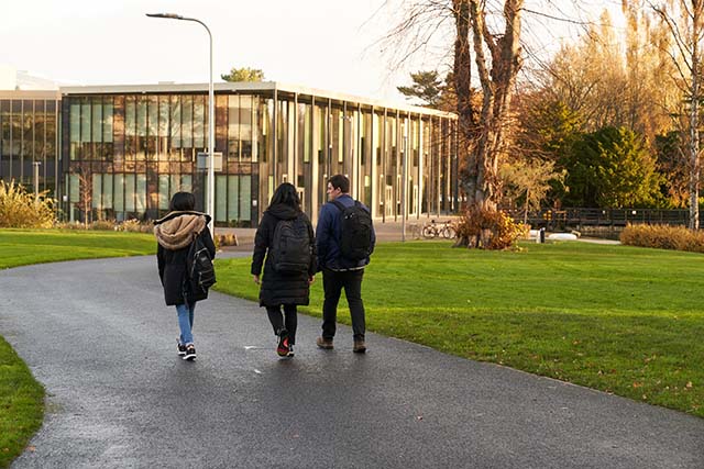 Three students walking across the Edinburgh campus