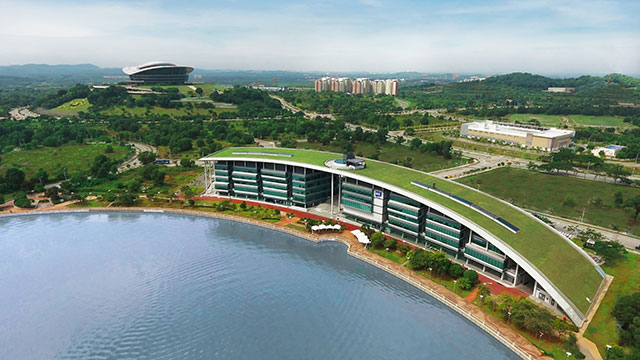 Aerial view of the Malaysia Campus building with grassed roof visible and lake in the foreground 